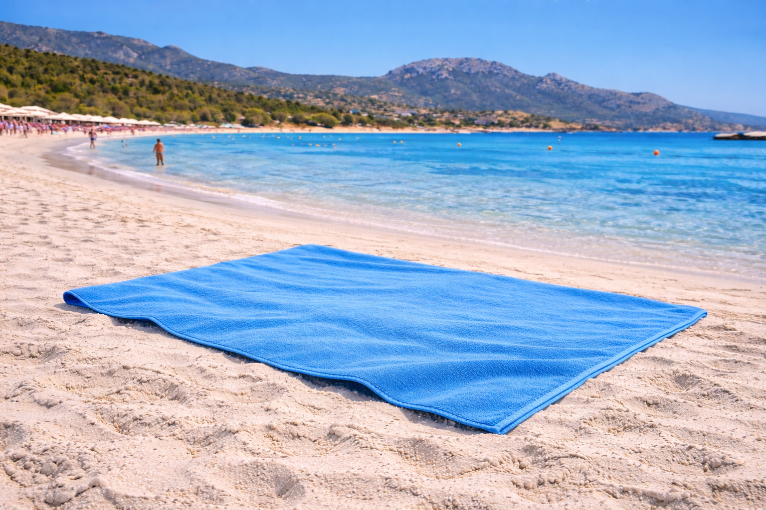 Blue beach mat on a sandy beach with clear blue water and mountains in the background