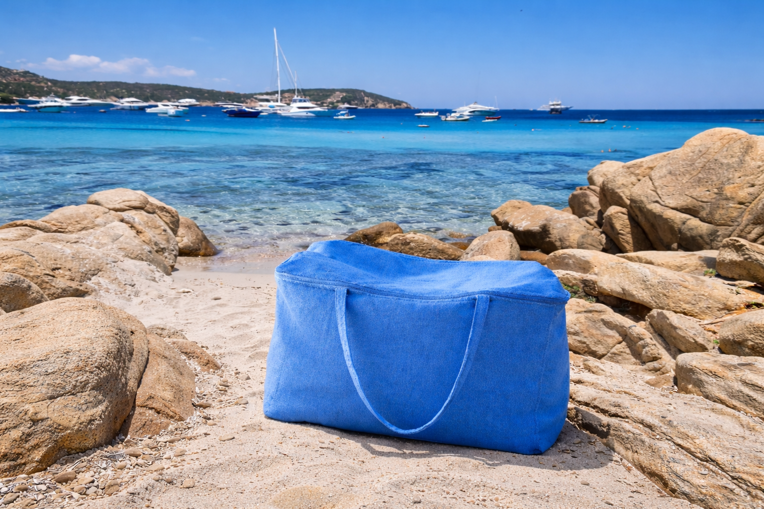Blue bag on a rocky beach with boats in the background