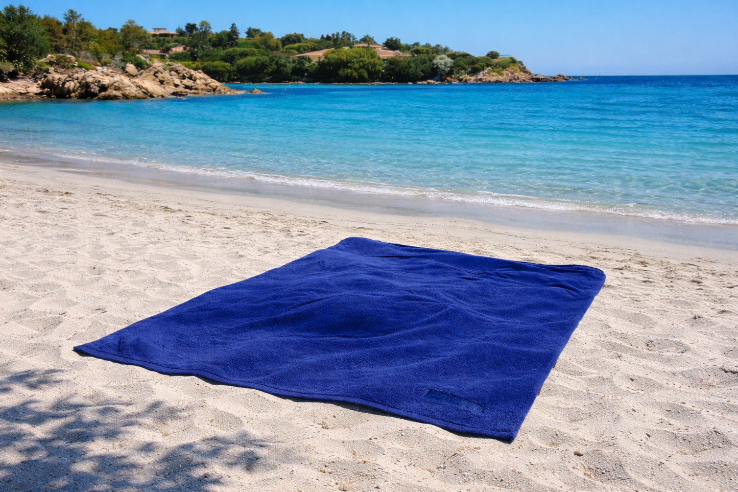 Blue towel on a sandy beach with ocean and sky in the background