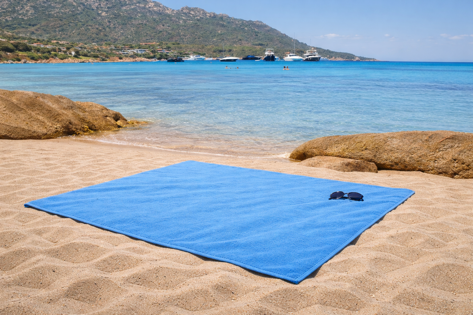 Blue sand mat on a sandy beach with clear blue water and mountains in the background