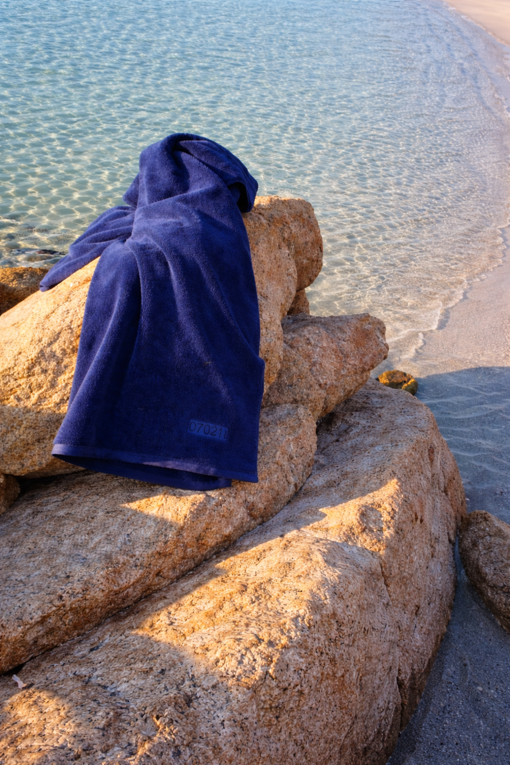 luxury blue towel draped over rocks on a beautiful beach at the Costa Smeralda